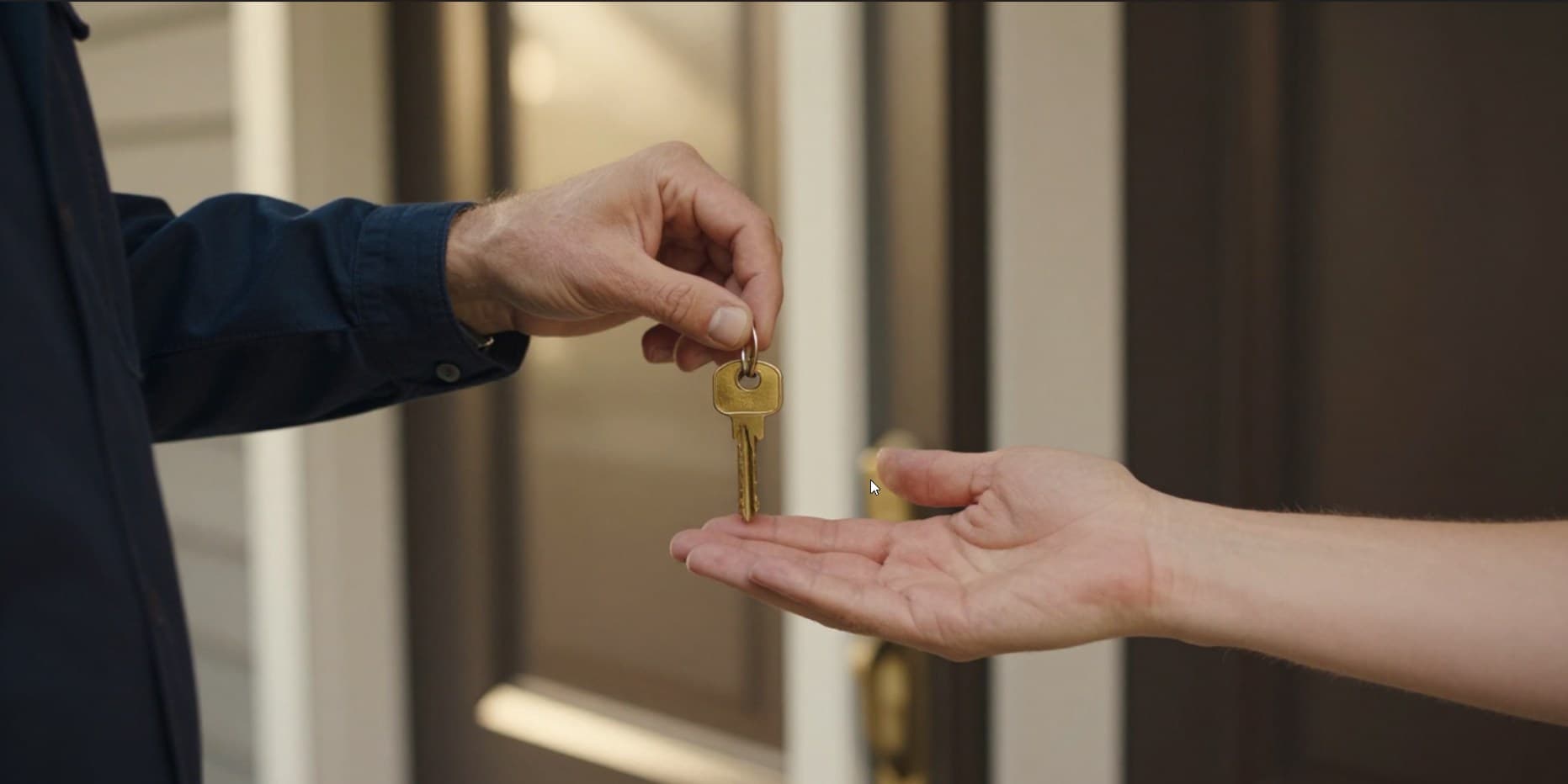 Locksmith handing over a freshly-cut key at a residential front door